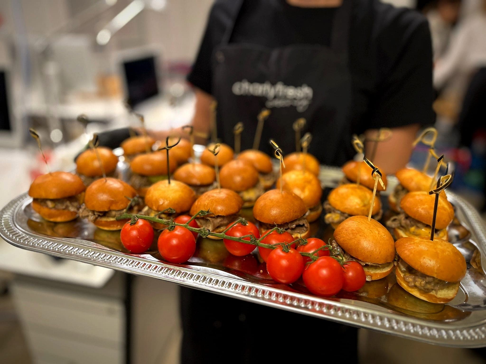 charlyfresh Catering — Mini-Burger-Platte mit Cocktailtomaten, serviert vom Team